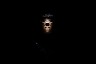 Spotlights casting dramatic shadows on an actor's face during a tense scene in a dark studio.