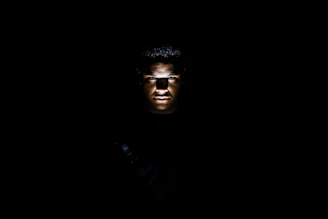 Spotlights casting dramatic shadows on an actor's face during a tense scene in a dark studio.