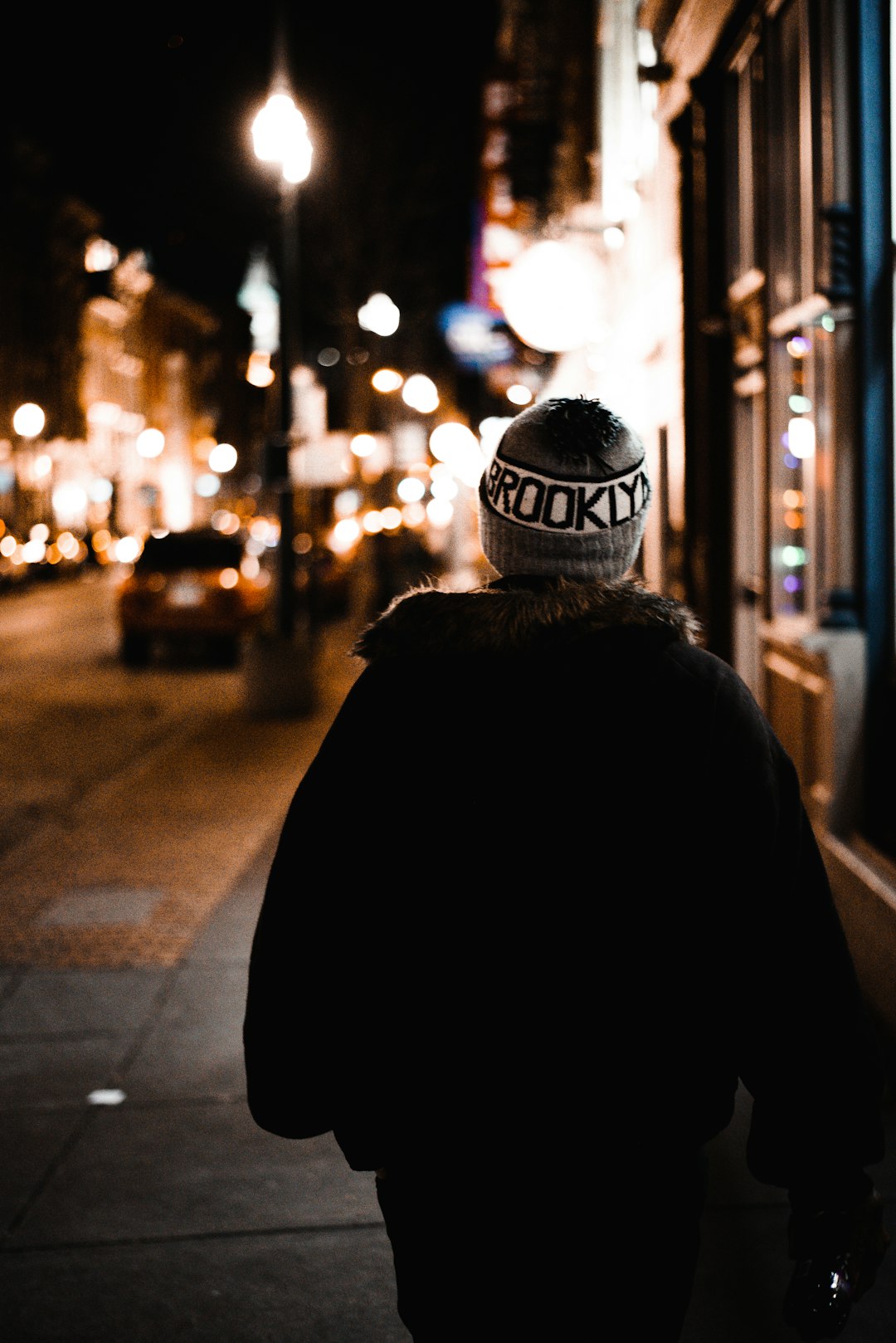 man walking on sidewalk at nighttime