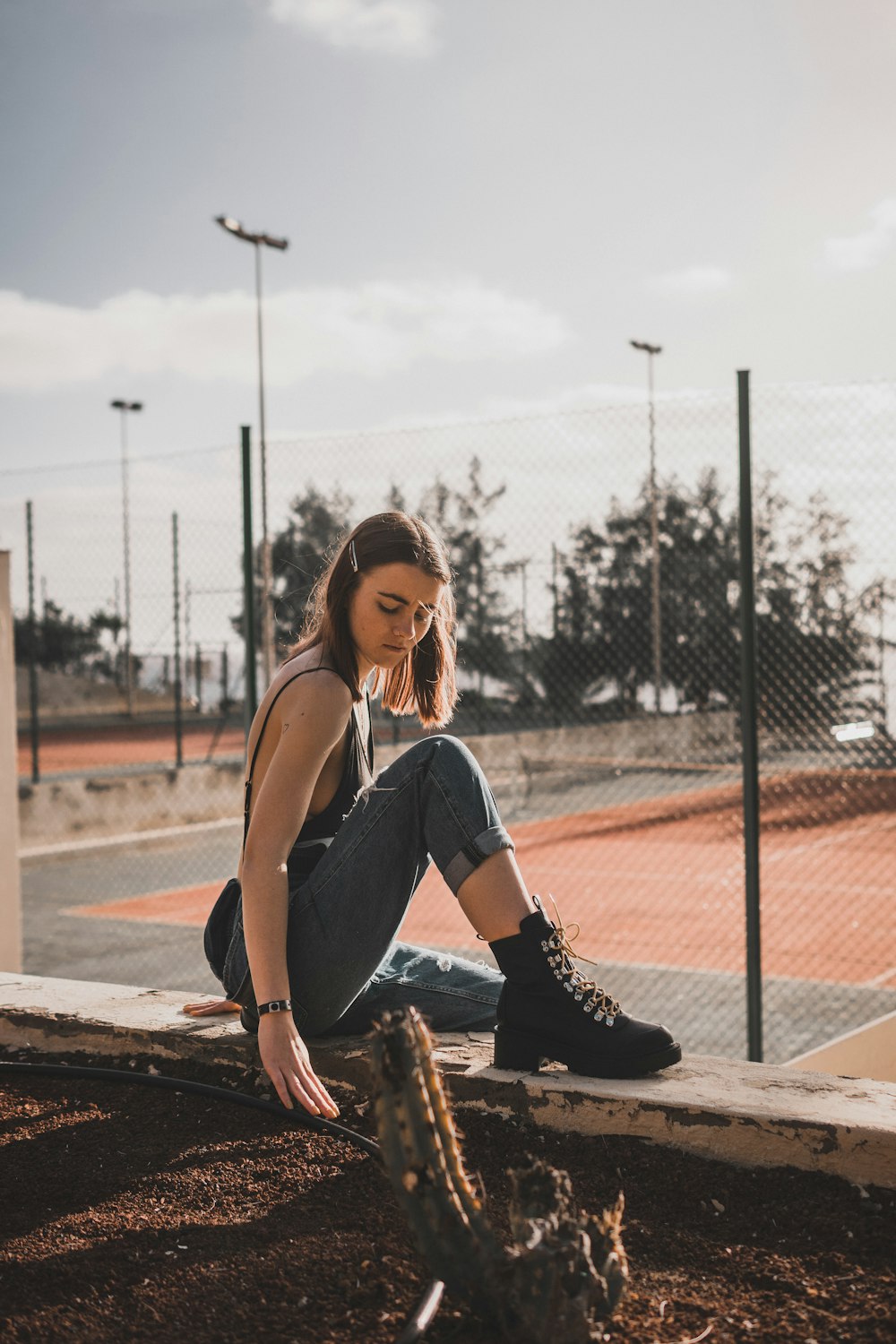 woman in denim jeans sits on grey concrete bench