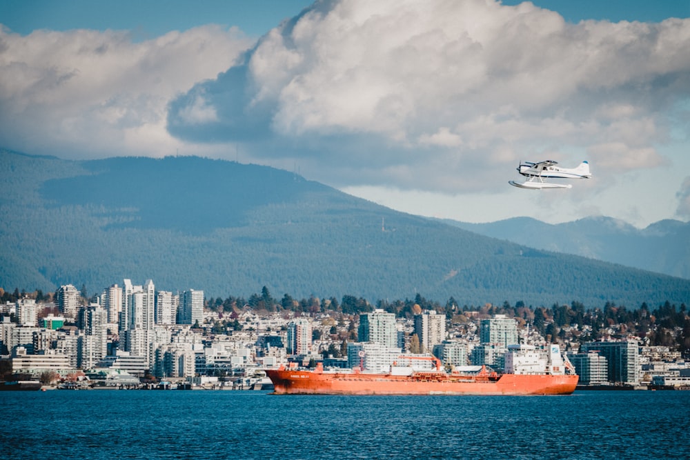 orange ship at middle of sea near buildings