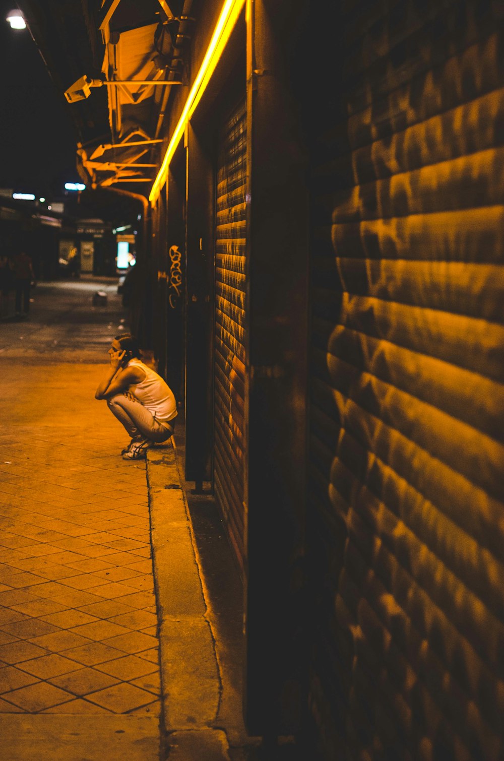woman sitting beside wall at night time