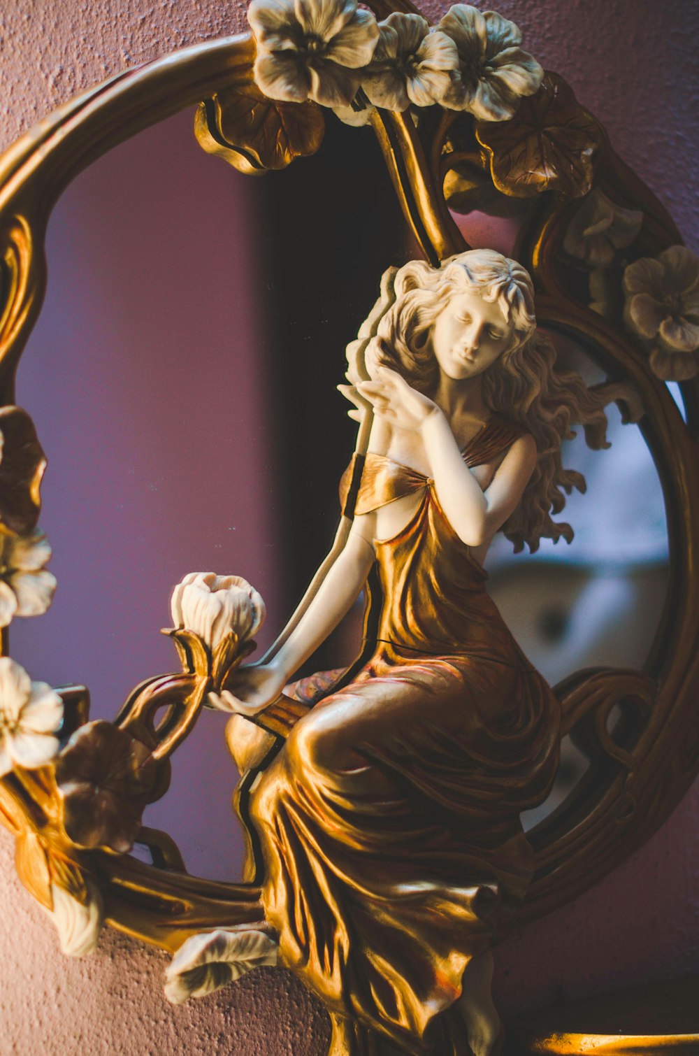 gold-colored and white floral woman framed mirror