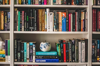 assorted-labeled book lot on white wooden shelf