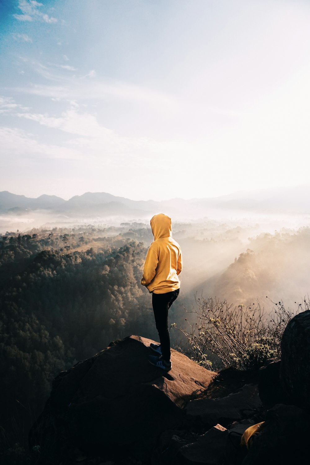 woman wearing yellow jacket standing on cliff