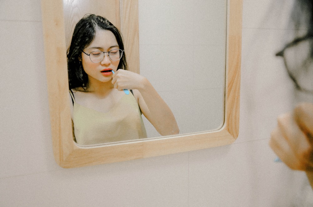 woman tootbrushing in front of mirror