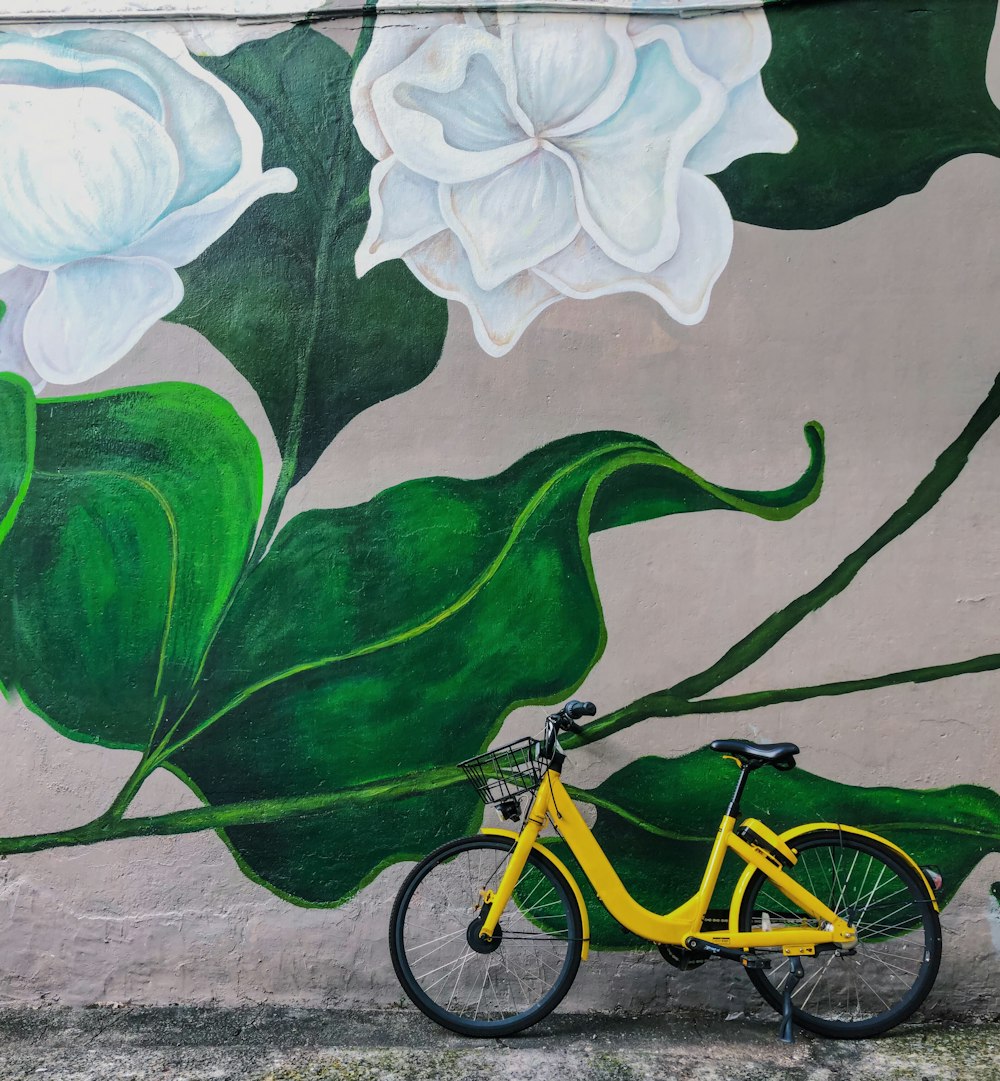 yellow bike parked beside white flowers graffiti during daytime