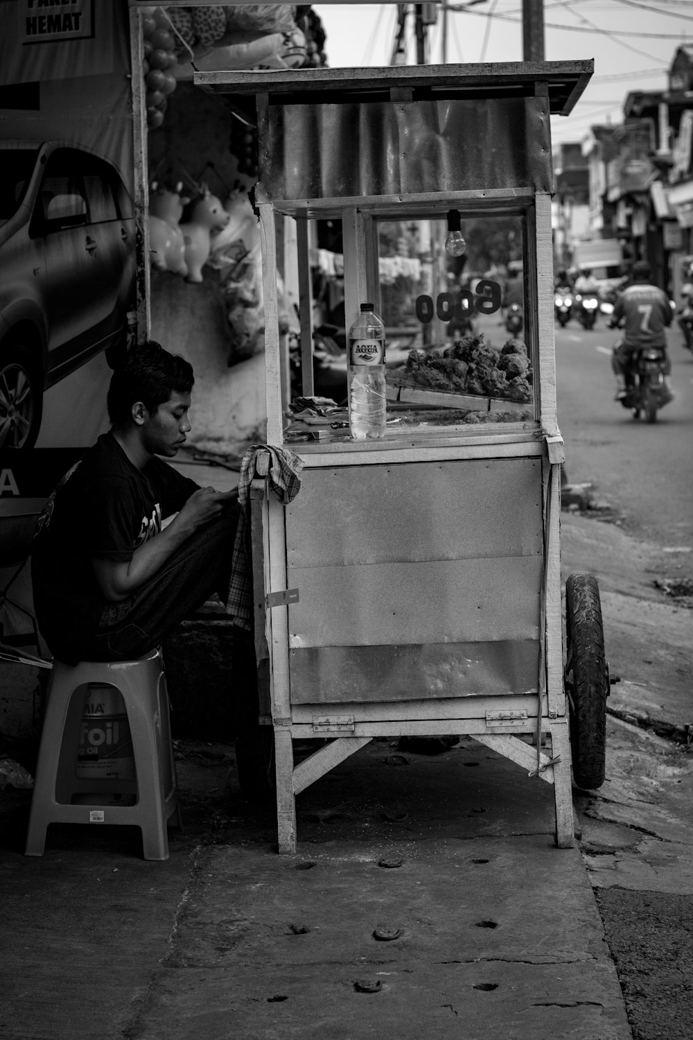 grayscale photography of man sitting on stool