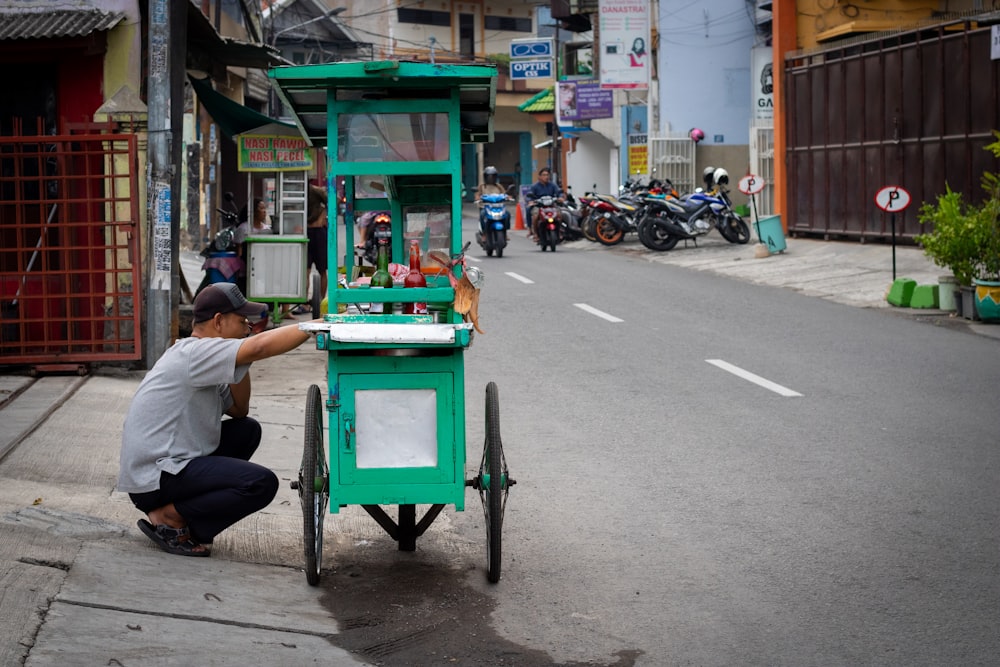 man squatting by the food cart