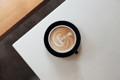 Elegant coffee cup with latte art on a minimalist black saucer.