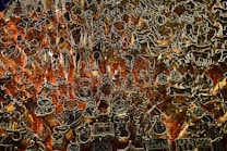 An intricate array of metal cookie cutters is organized against a pegboard with red-orange backlighting. The cutters are various shapes including animals, stars, trees, and other festive designs.