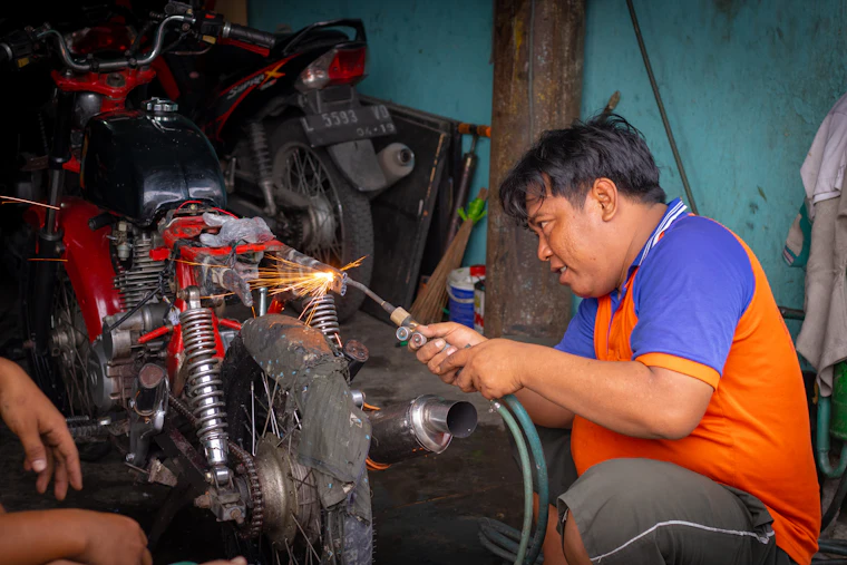 Technician inspecting under the hood of a vehicle in the shop