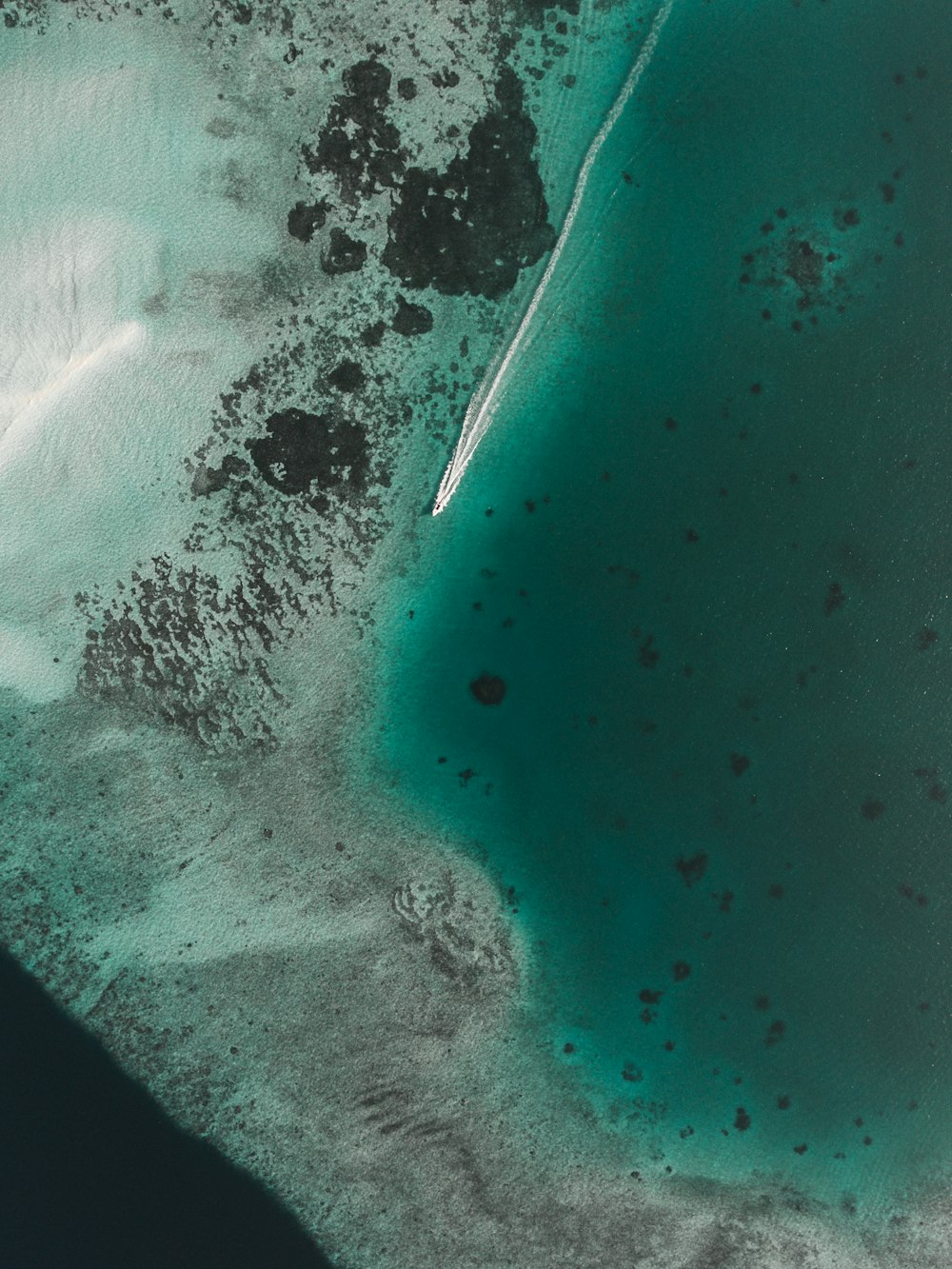 barco deixando hélice branca lavar na superfície do mar verde claro