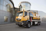 A sleek orange-accented Beylor truck parked at a logistics hub during sunrise.