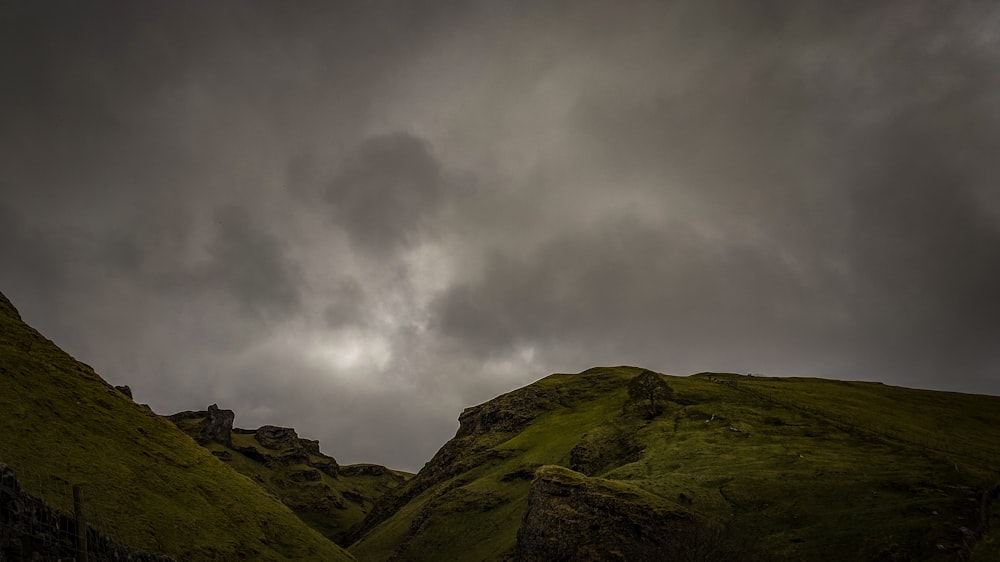 green grass field under nimbus clouds