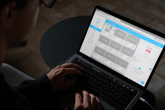 A person using a laptop to build a website with visual tools on the screen.