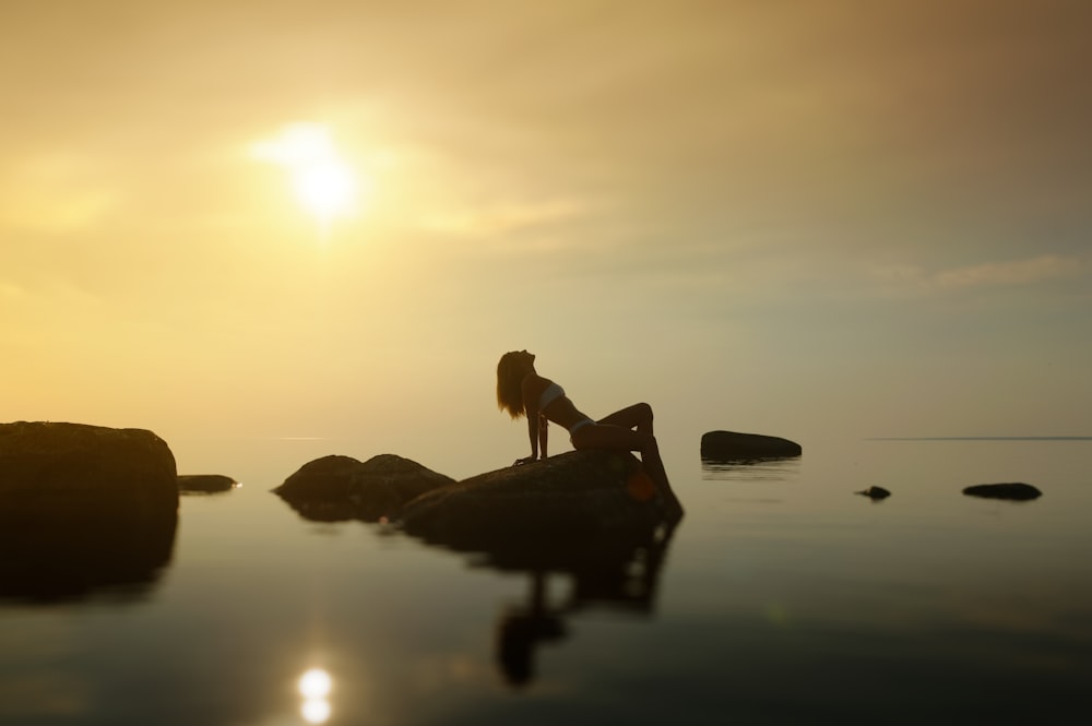 woman sitting on stone near water