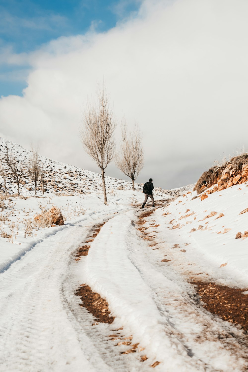 man walking on snow covered road during daytime