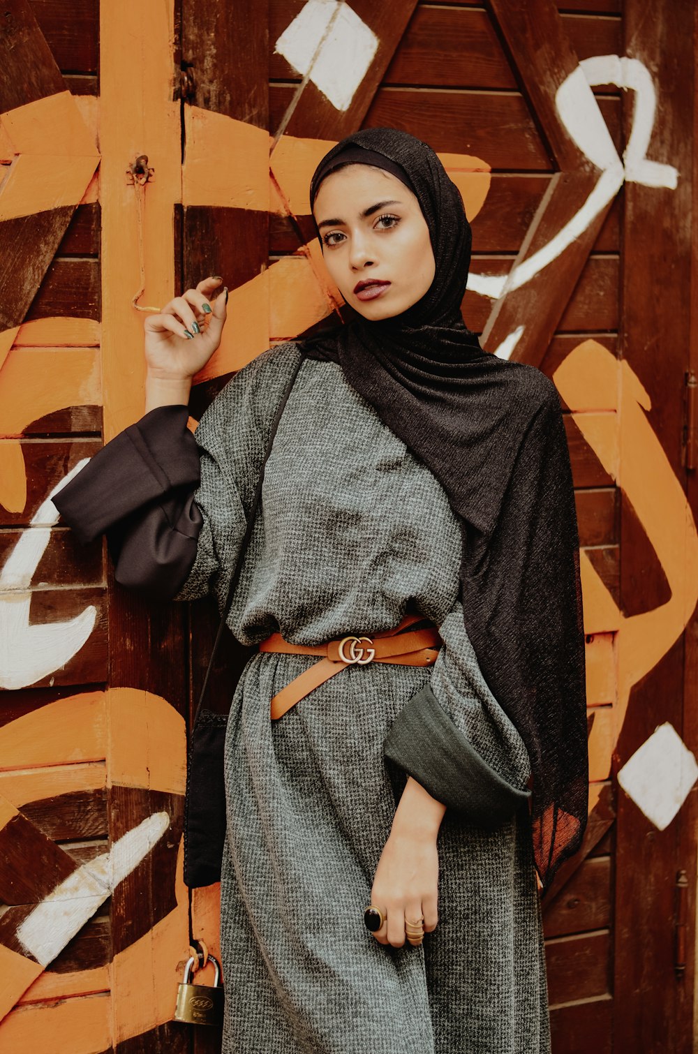 woman wearing black hijab standing near art covered door