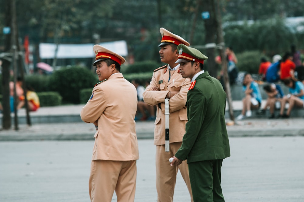 three men in law enforcer uniform standing beside pavement