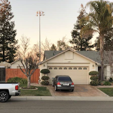 A cozy suburban home with a car parked in the driveway under a clear sky.