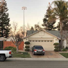 A cozy suburban home with a car parked in the driveway under a clear sky.