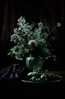 Still life composition featuring flowers in a rustic vase with subtle shadows.
