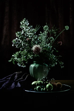 Still life composition featuring flowers in a rustic vase with subtle shadows.