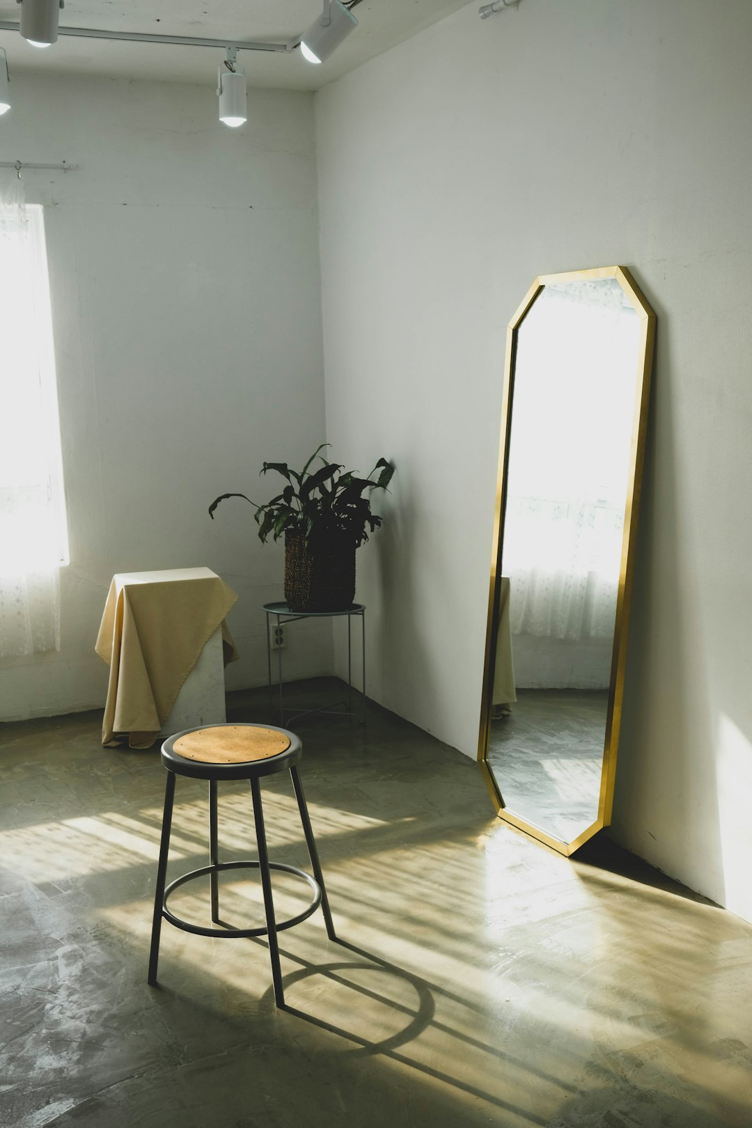round brown wooden stool near leaning mirror