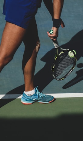 woman holding tennis ball and racket