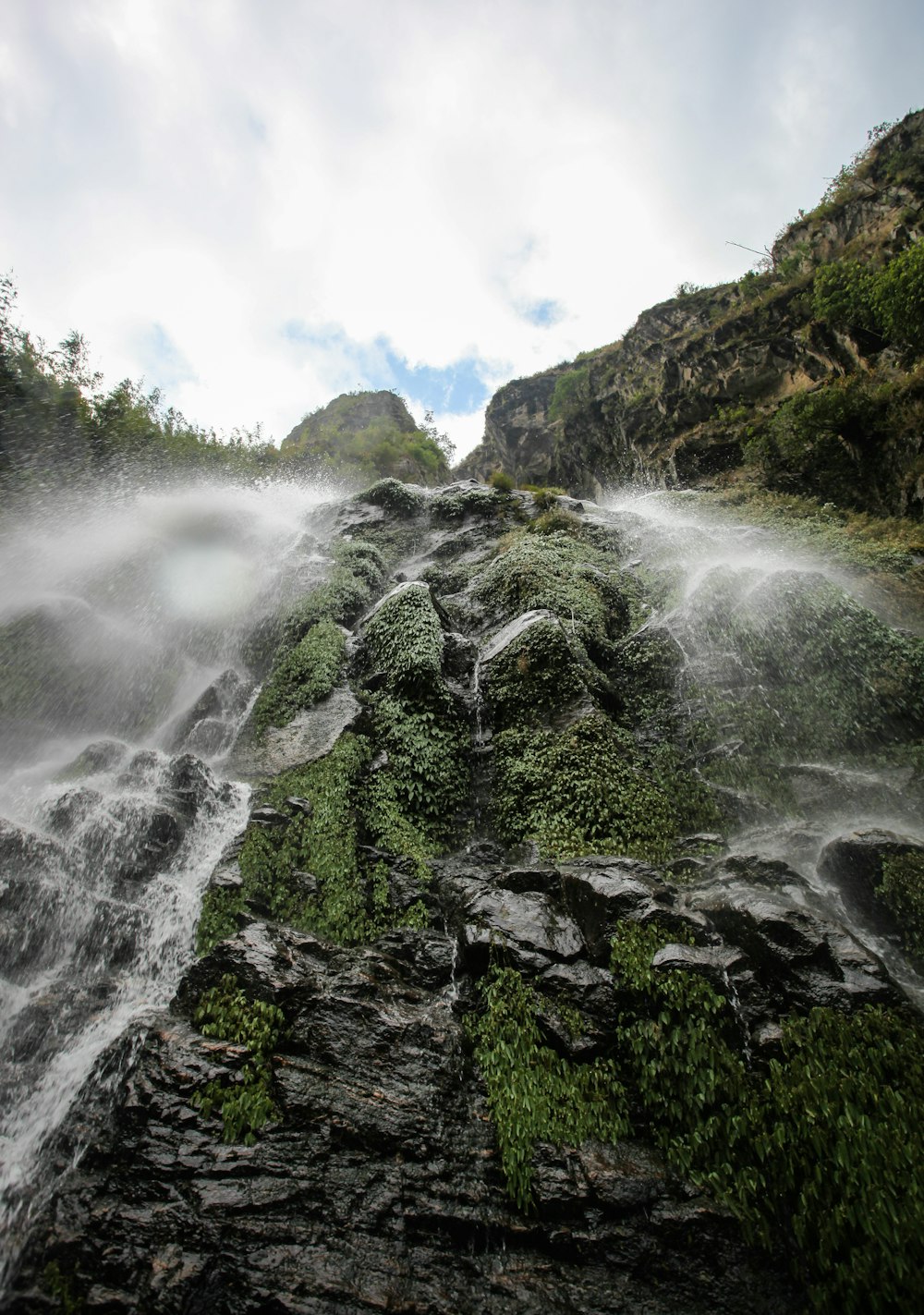 waterfalls with moss covered rocks in high-angle photography during daytime