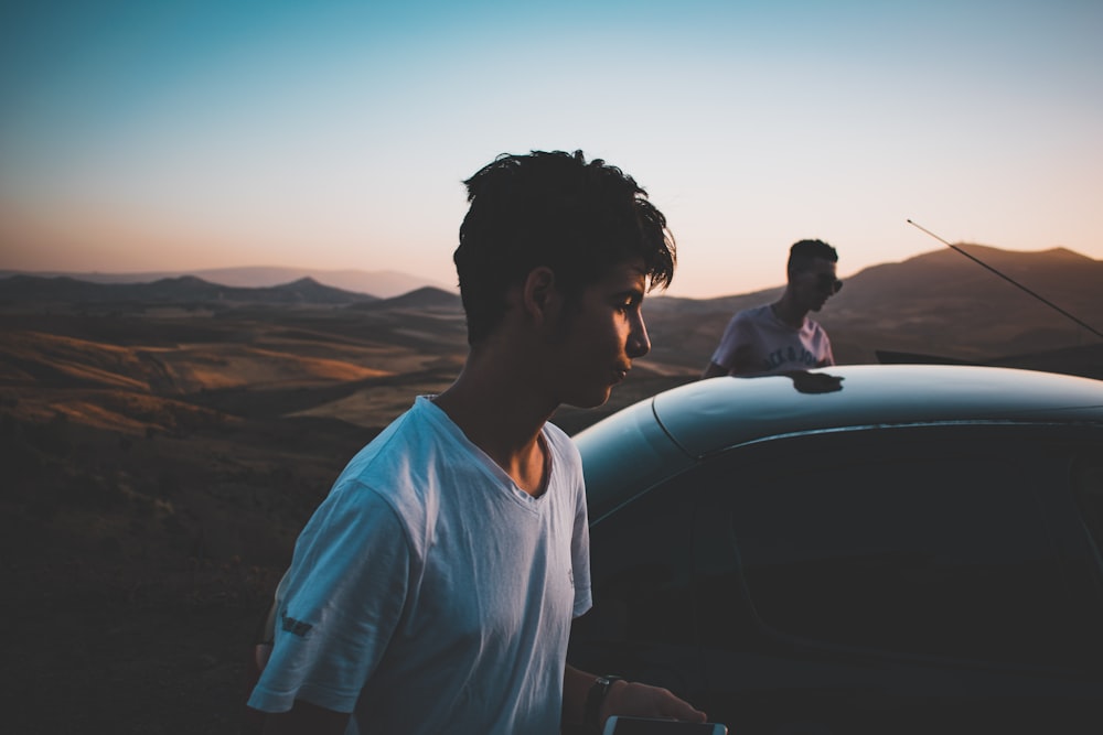 two men standing beside car