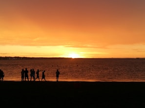A group of travelers enjoying a sunset on a pristine tropical beach in Southeast Asia.