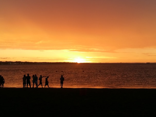 A smiling group of travelers enjoying a serene sunset at a luxury international destination.