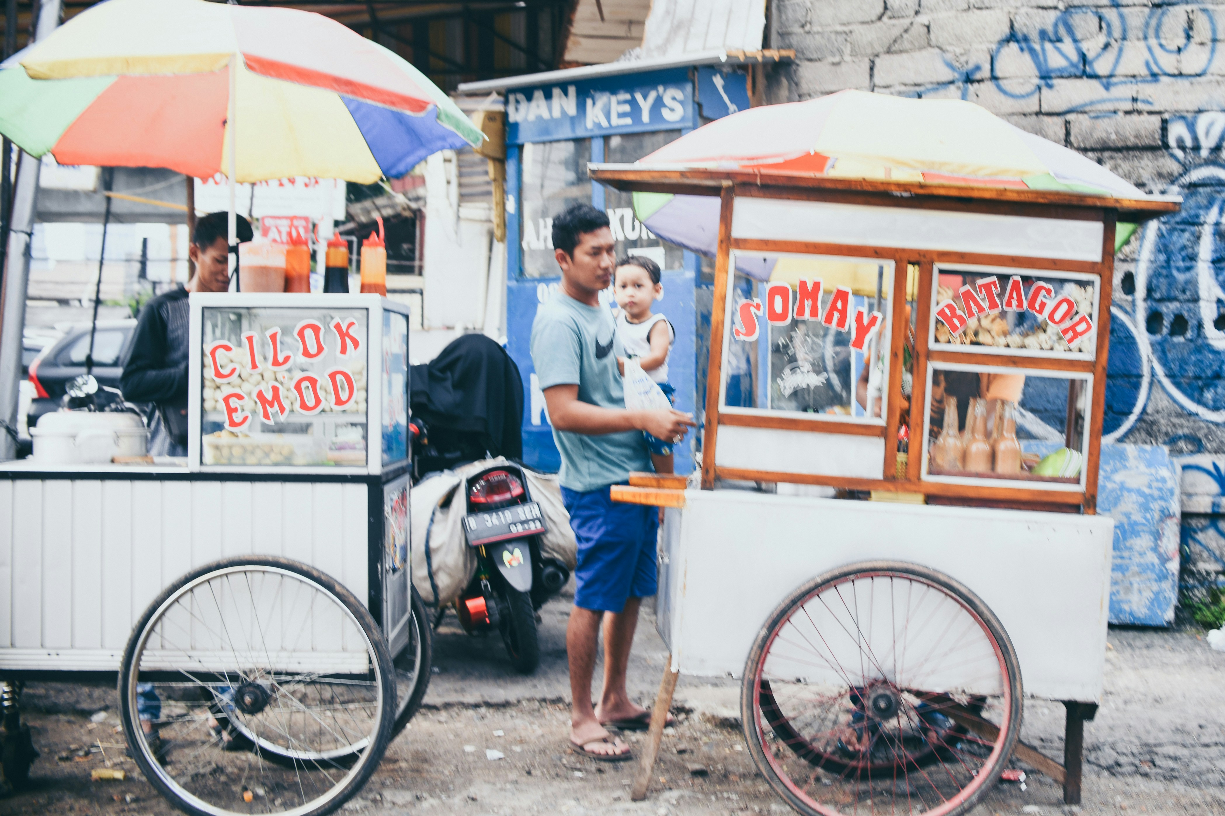 man carrying baby between white bicycle carts, 