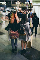 Fashionable Barbie-style girls carrying chic shopping bags, laughing and walking down a lively street.