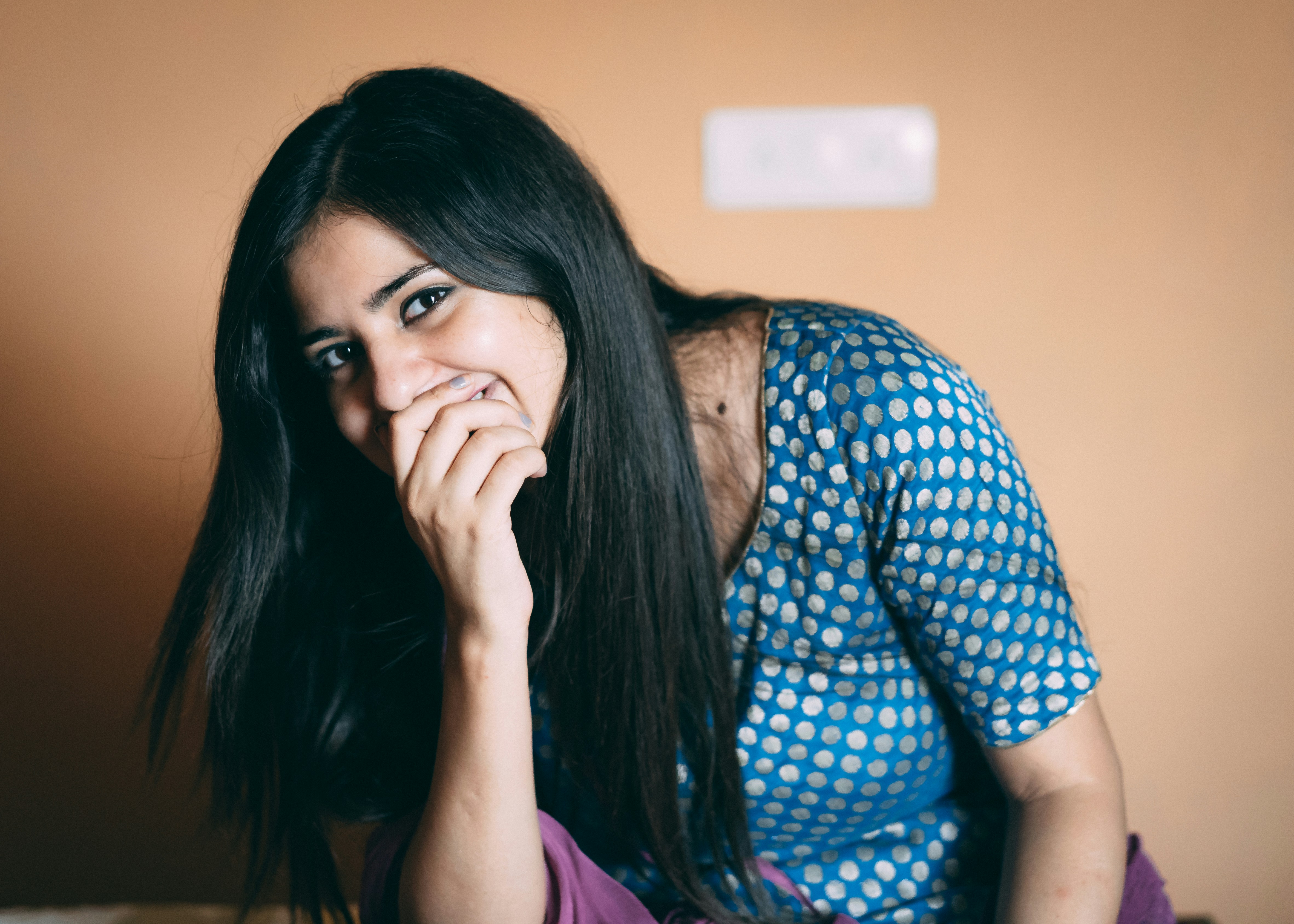 woman smiling while holding mouth