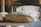 Freshly baked bread with a golden crust resting on a wooden paddle in front of a rustic oven. The bread appears soft and fluffy, indicative of a perfect bake. The background is slightly blurred, focusing the attention on the bread and the warm ambiance of a traditional bakery.