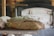 Freshly baked bread with a golden crust resting on a wooden paddle in front of a rustic oven. The bread appears soft and fluffy, indicative of a perfect bake. The background is slightly blurred, focusing the attention on the bread and the warm ambiance of a traditional bakery.