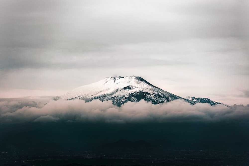 灰色の空の下に雪に覆われた黒い山