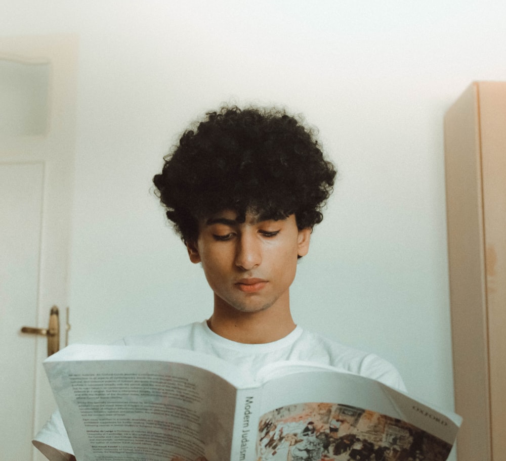 man in white shirt while reading book