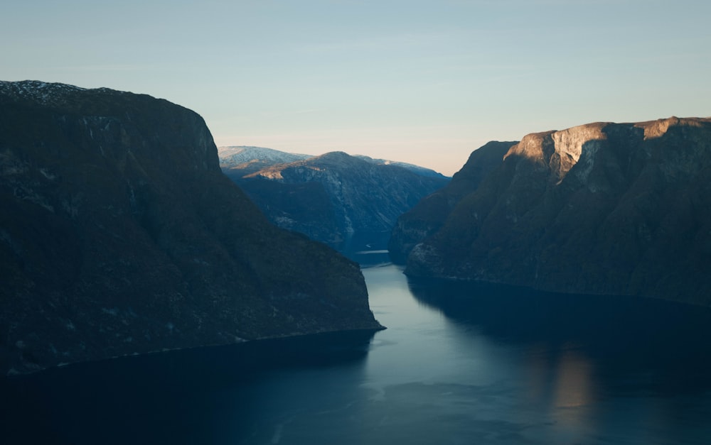 calm body of water beside rock formation during daytime