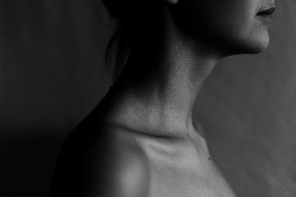Artistic black-and-white portrait capturing the subtle curve of a shoulder and neck in gentle shadow