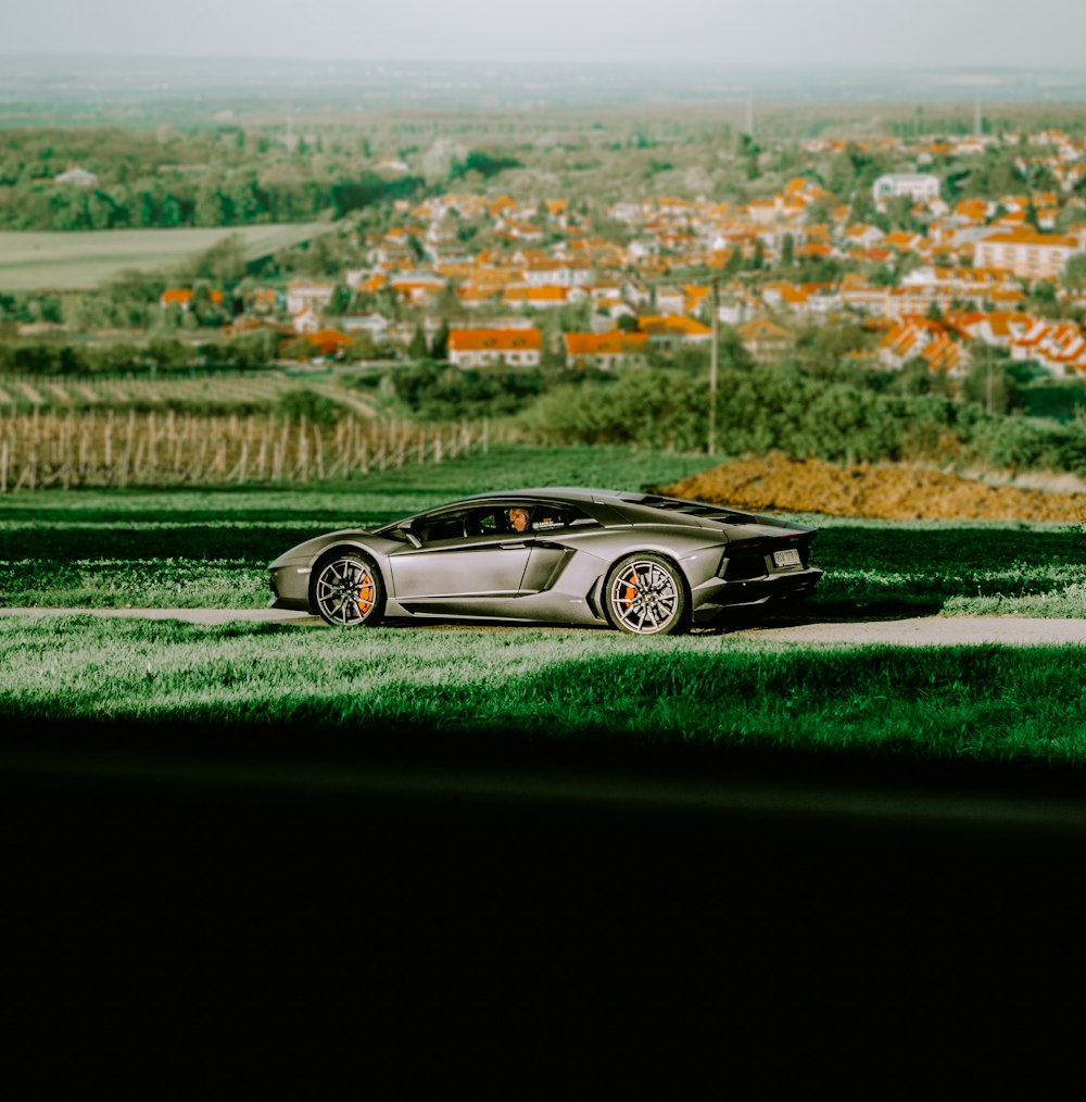 gray Lamborghini sports coupe parked on road near city during daytimee