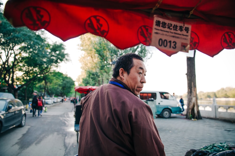 man wearing brown jacket looking back during daytime