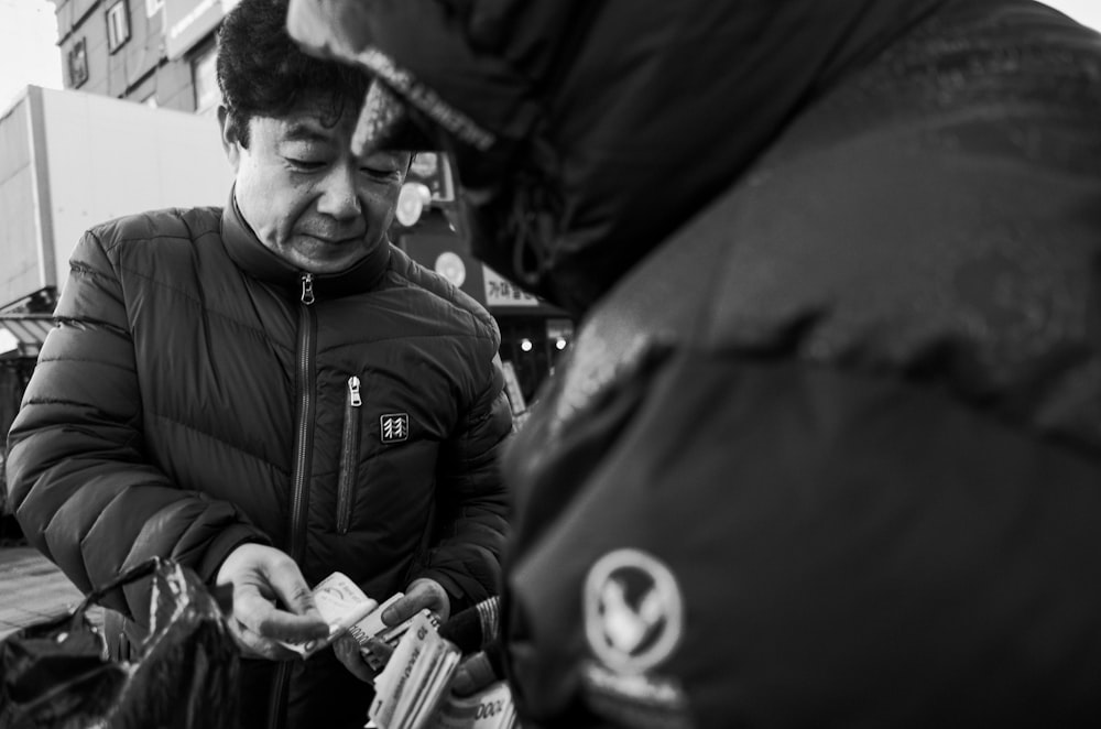 grayscale photography of man wearing zip-up bubble jacket