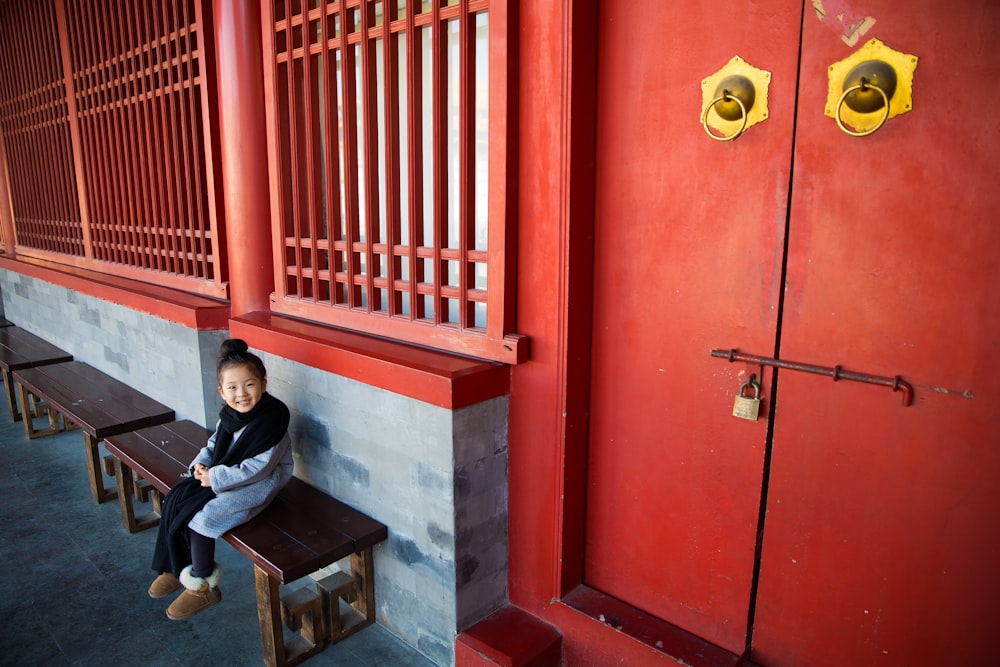 child on bench beside a close door