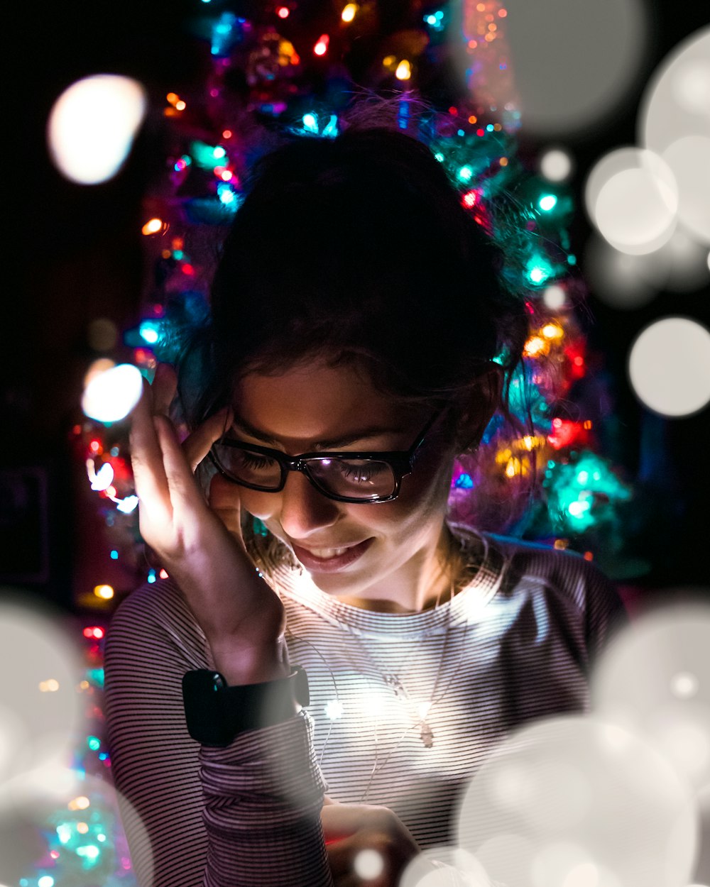 smiling woman standing under multicolored string lights
