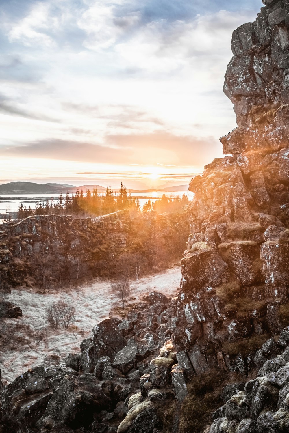 rocky hill beside river across woods aty sunrise