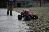 Two kids laughing together while playing with a remote-controlled car outdoors.
